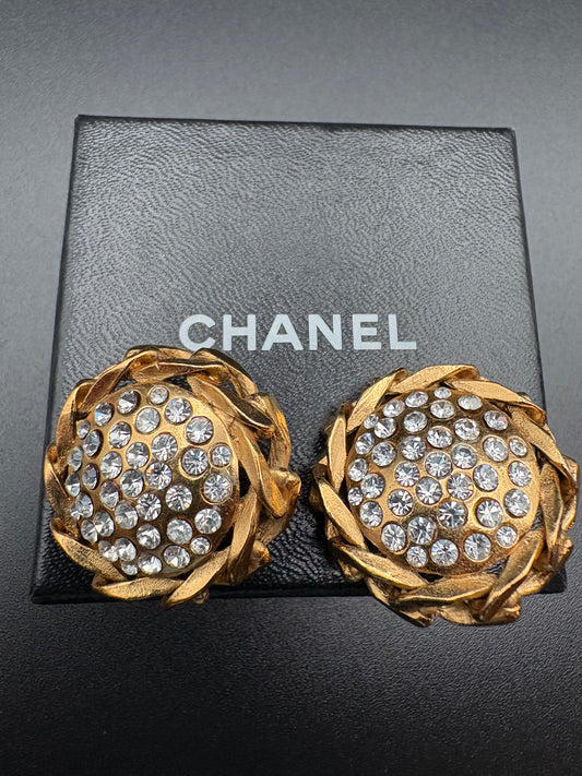 Gold earrings with crystal embellishments on a Chanel box